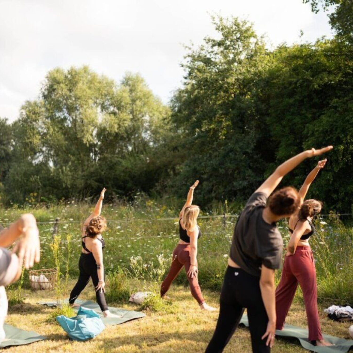 043_Bild_06-MuB_Yoga-und-Mantra_SO-10-00_moya-yoga Menschen praktizieren Yoga auf einer Wiese