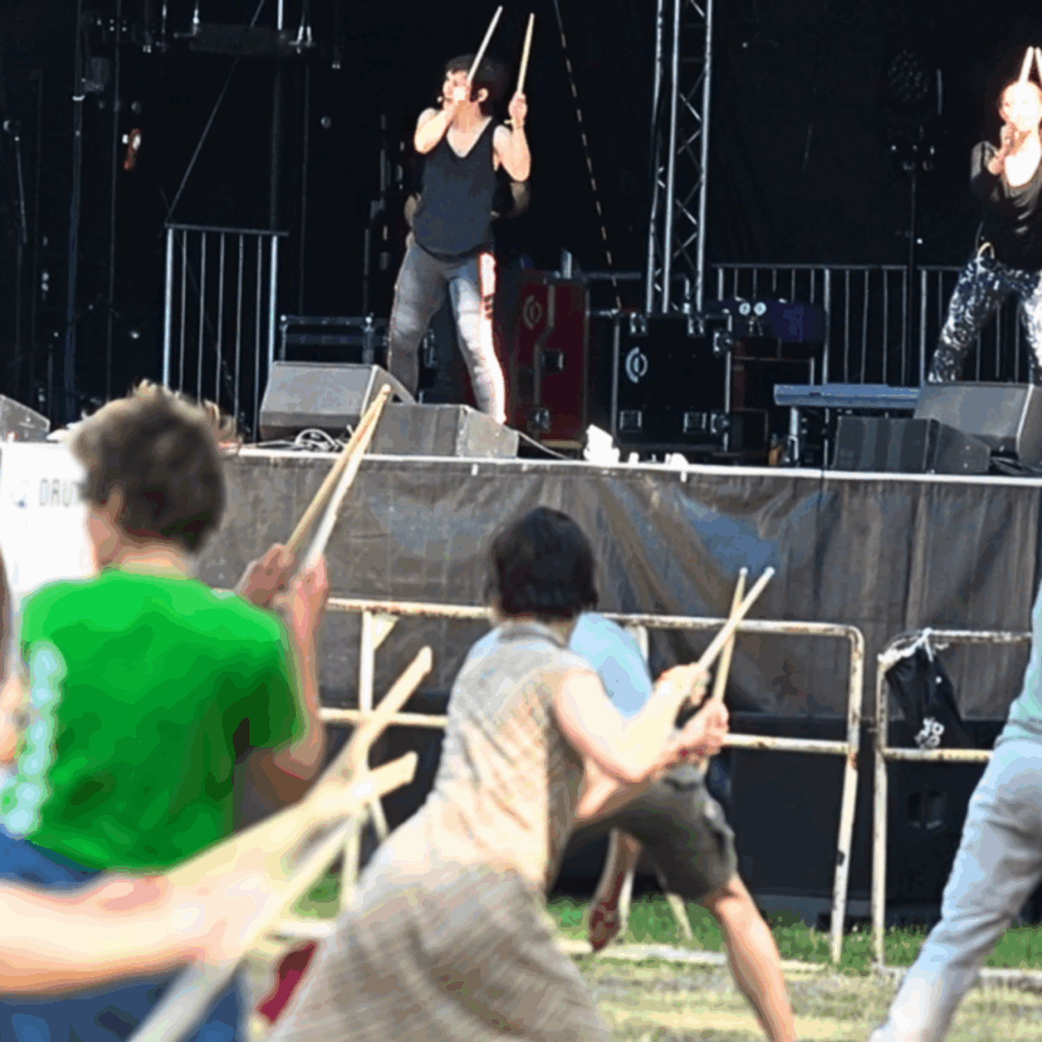 050_Bild_06-MuB_Drum-Fitness_MO-10-00 Menschen bewegen sich in einer dynamischen Choreographie auf der Hauptwiese des OPEN OHR Festivals und schwingen dabei Schlagzeugstöcke.