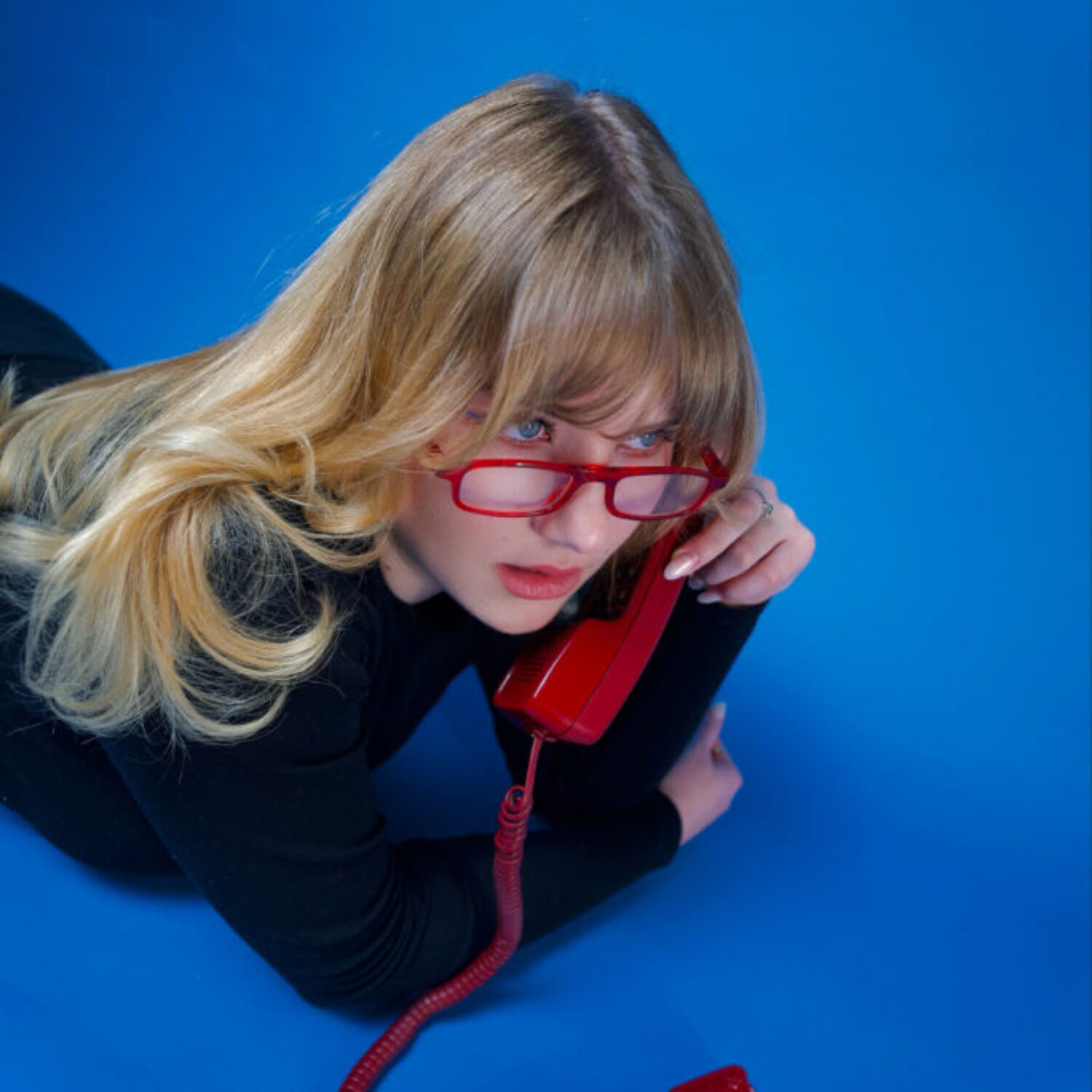098_Bild_10-Musik_Dilla_SO-21-00_Lola-Schreiner Dilla liegt auf dem Boden und hält sich ein rotes Kabeltelefon ans Ohr